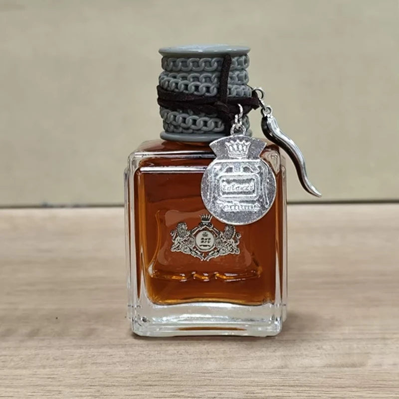 Flacon de parfum ambré Jean Miss en gros plan — bouchon chaîne grise et pendentif argenté