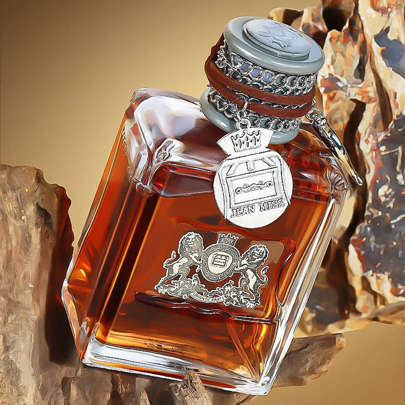 Flacon de parfum ambré à bouchon argenté orné, posé sur bois de oud